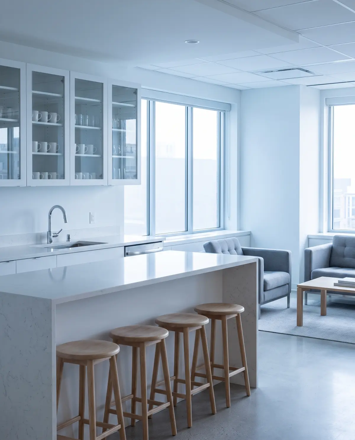 A spotless office kitchenette with a white quartz counter and a gleaming steel sink